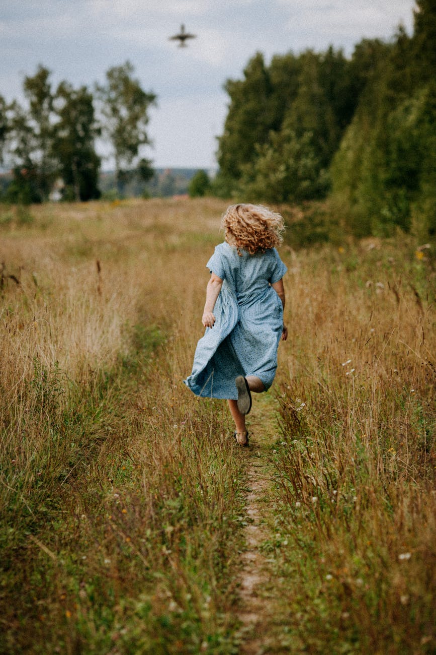 a woman in a blue dress running on a grassy field